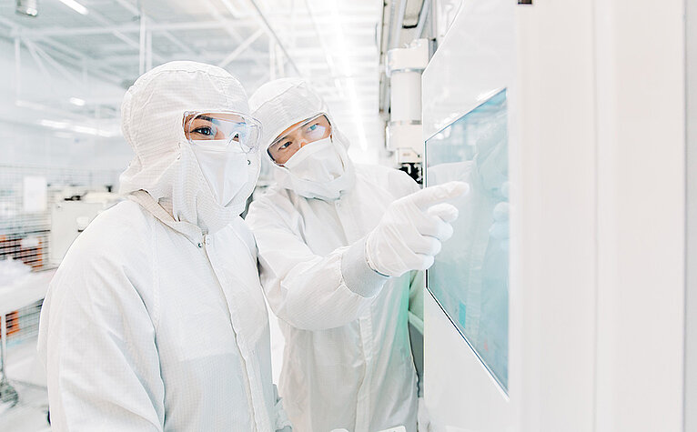 Two Lam Research employees wearing protective clothing in the laboratory in Villach, Austria 