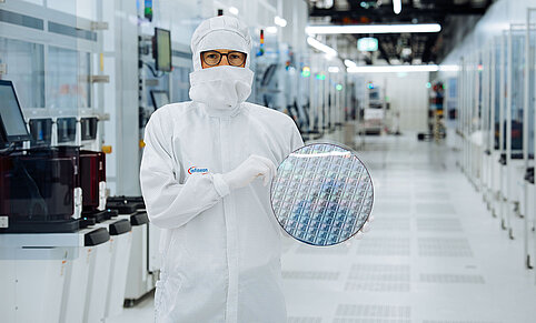 Ein Techniker im Reinraum von Infineon Technologies in Villach, Österreich, hält einen 300 mm Galliumnitrid-Wafer.