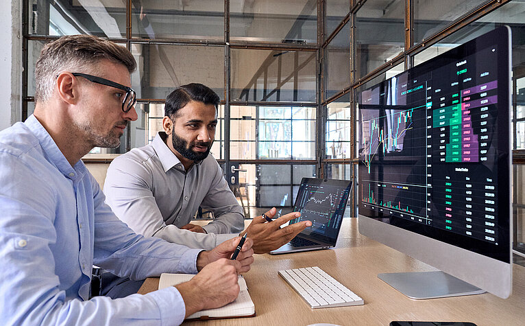 Zwei Krypto-Broker vor dem Bildschirm: Österreich bietet internationalen Unternehmen mit klarer Regulierung und Rechtssicherheit ein verlässliches Umfeld für digitale Finanzinnovationen.